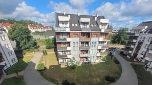 Un edificio residencial de varios pisos con balcones, un camino curvo y un pequeño jardín.