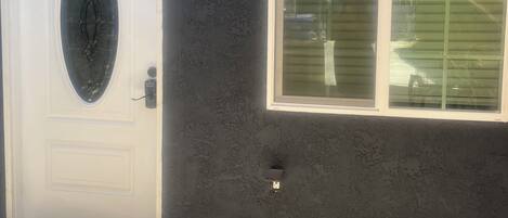 A house with a white door, a large window, and a welcome mat.