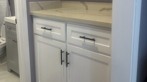 A kitchen with white cabinets, a marble countertop, and a grey wall. - Guest House in the beautiful City of Downey (Downey)