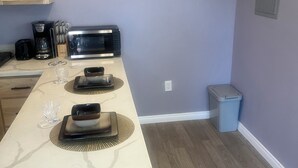 A kitchen with a countertop, a toaster, a coffee maker, and a trash can. - Guest House in the beautiful City of Downey (Downey)
