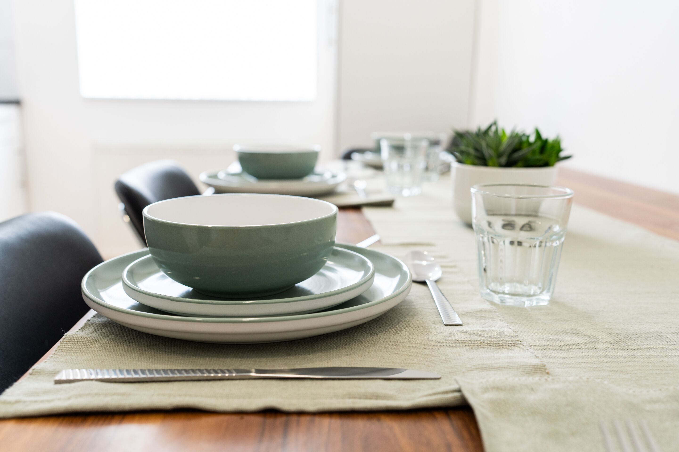 Une table à manger dressée avec des assiettes, des bols, un verre et des couverts.