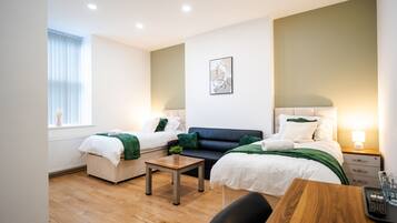 Ein modernes Hotelzimmer mit zwei Betten, einer Couch, einem kleinen Tisch und einem Sessel.