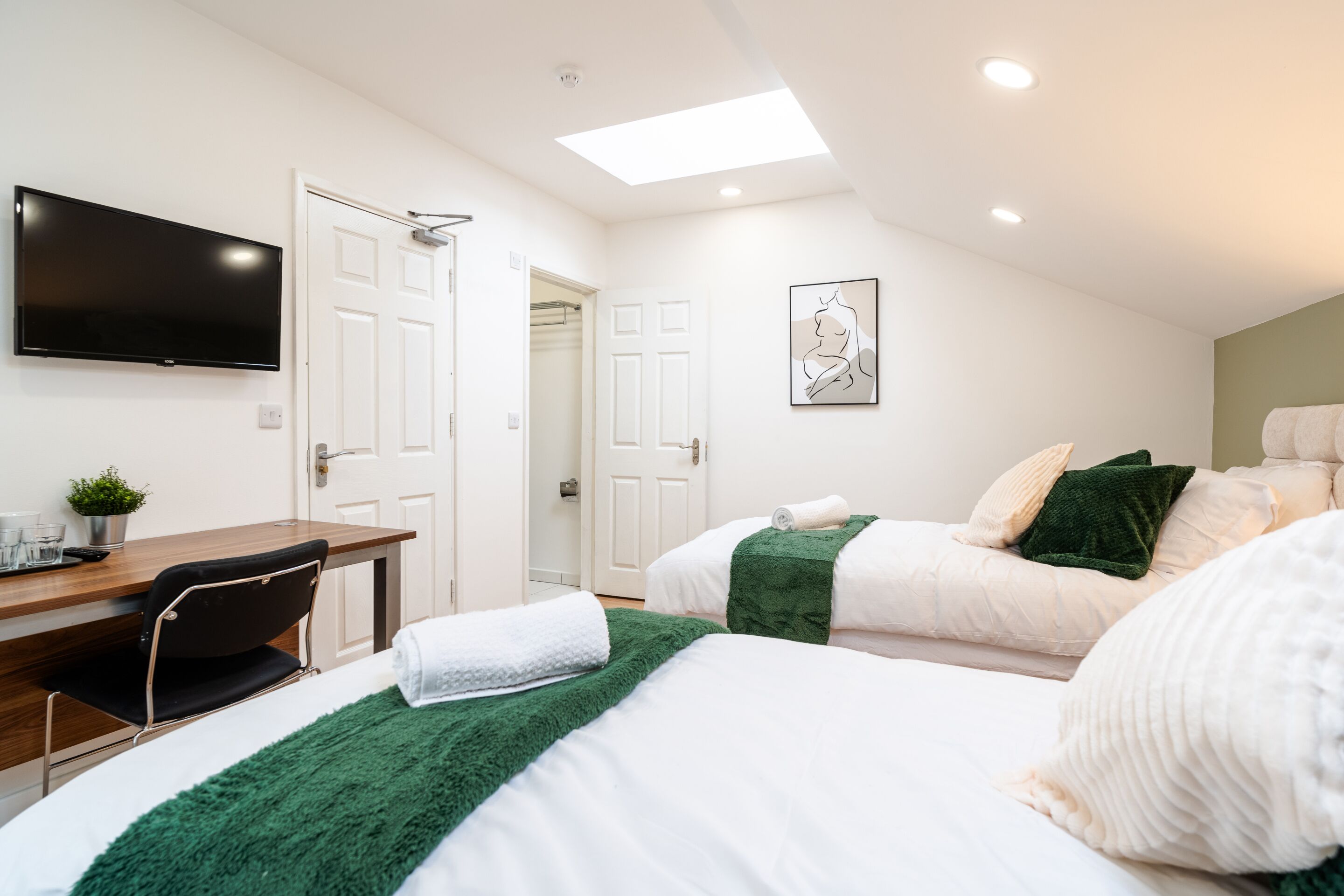 Una habitación de hotel con una cama, un escritorio, una silla, un televisor y un cuadro en la pared.