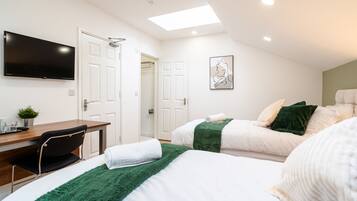 Una habitación de hotel con una cama, un escritorio, una silla, un televisor y un cuadro en la pared.