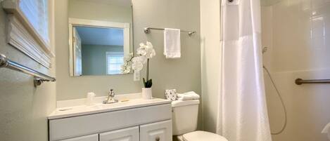 A bathroom with a vanity, toilet, and shower curtain.