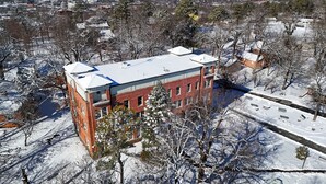 A snow-covered building with a brick facade, surrounded by trees and a clear sky. - Mount Sequoyah Center (Fayetteville)