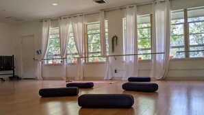 A spacious room with large windows, a ballet barre, and several black ottomans on the wooden floor. - Mount Sequoyah Center (Fayetteville)