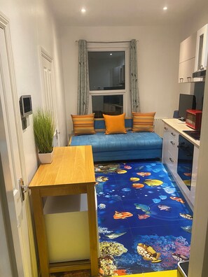 Relax in this cozy space with a sofa, table, and vibrant carpet featuring an underwater theme.