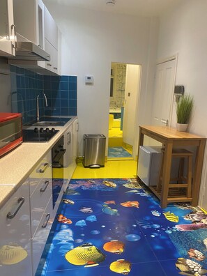 Kitchen with modern appliances, including a range hood, oven, and microwave, and a wooden table with a potted plant.