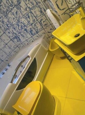 Bathroom features a unique tile pattern and a yellow sink and toilet.
