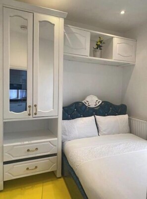 Comfortable bedroom with a wardrobe, bed, and potted plant.