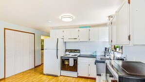 Una cocina con armarios blancos, estufa, refrigerador y microondas.