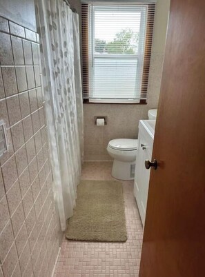 Bathroom features a toilet, window with blinds, and a door.
