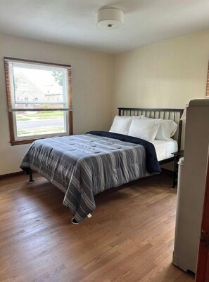 Relax in this cozy space with a single bed, wooden floor, and a window offering a view of the outside.