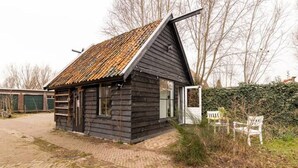 Une petite cabane en bois sombre, dotée d’un toit en pente et d’une porte donnant sur l’intérieur.