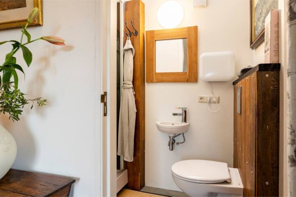 Un baño pequeño con un lavamanos blanco, un inodoro y un armario de madera.