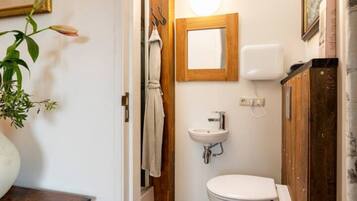 Un baño pequeño con un lavamanos blanco, un inodoro y un armario de madera.