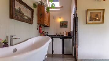 Bany amb banyera autònoma, un petit lavabo i una finestra sobre el lavabo.