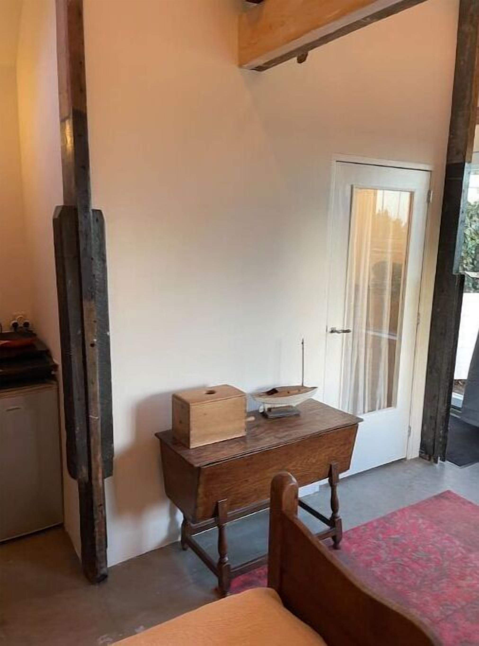 A room with a wooden desk, a chair, a small cabinet, and a door with a curtain.