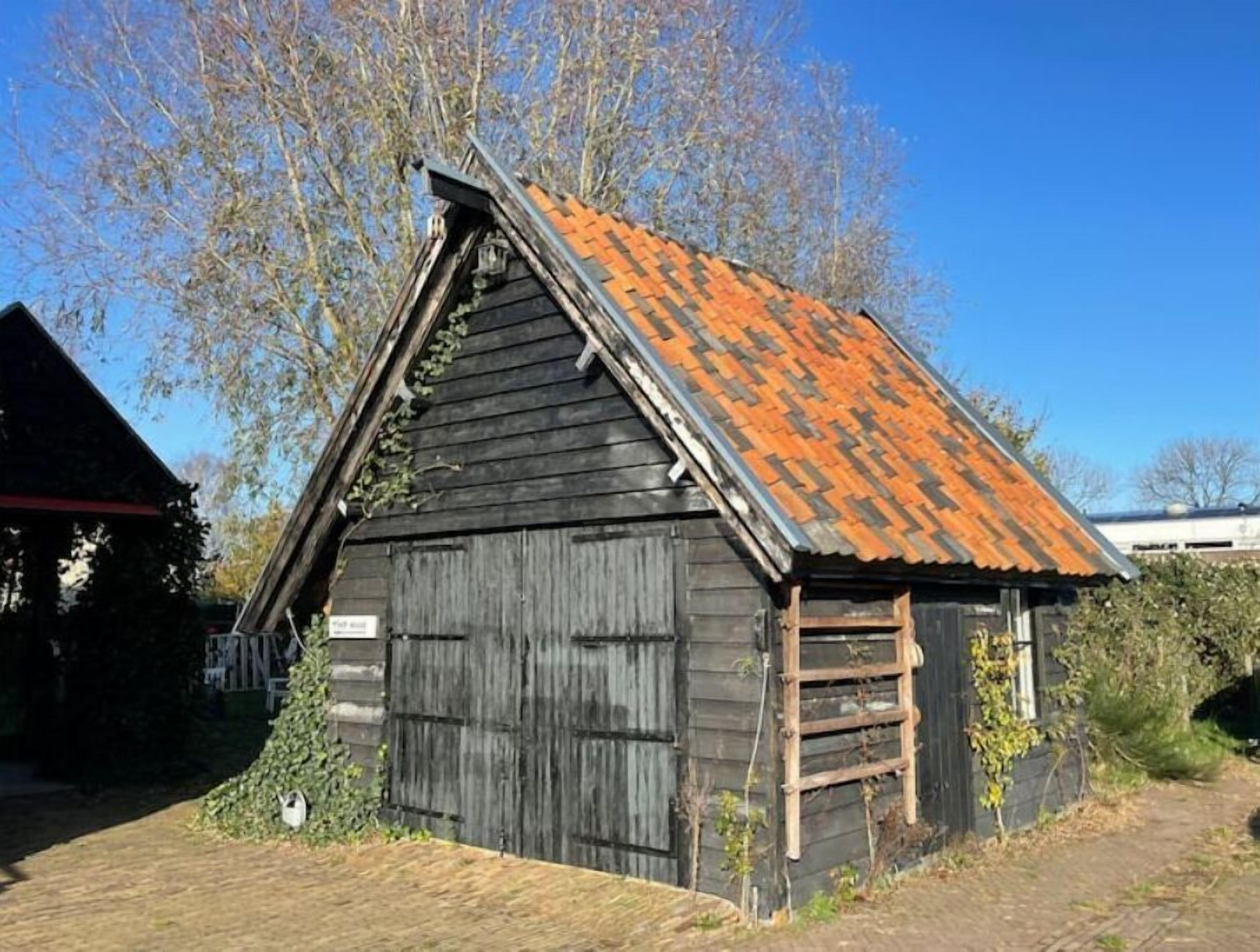 A rustic wooden building with a sloped roof and a wooden ladder leaning against it.