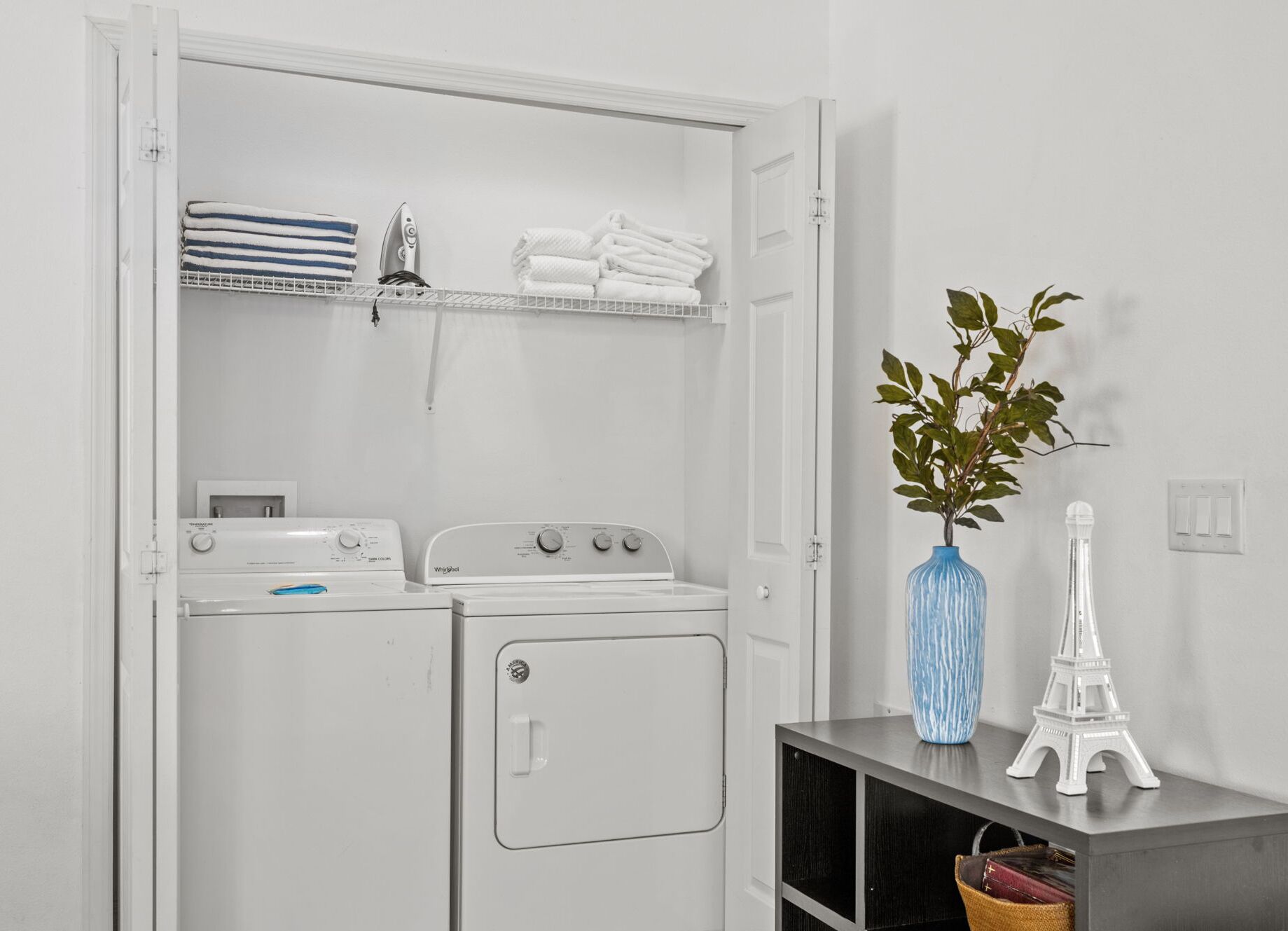 A laundry room with stacked towels, an iron, and a washing machine.