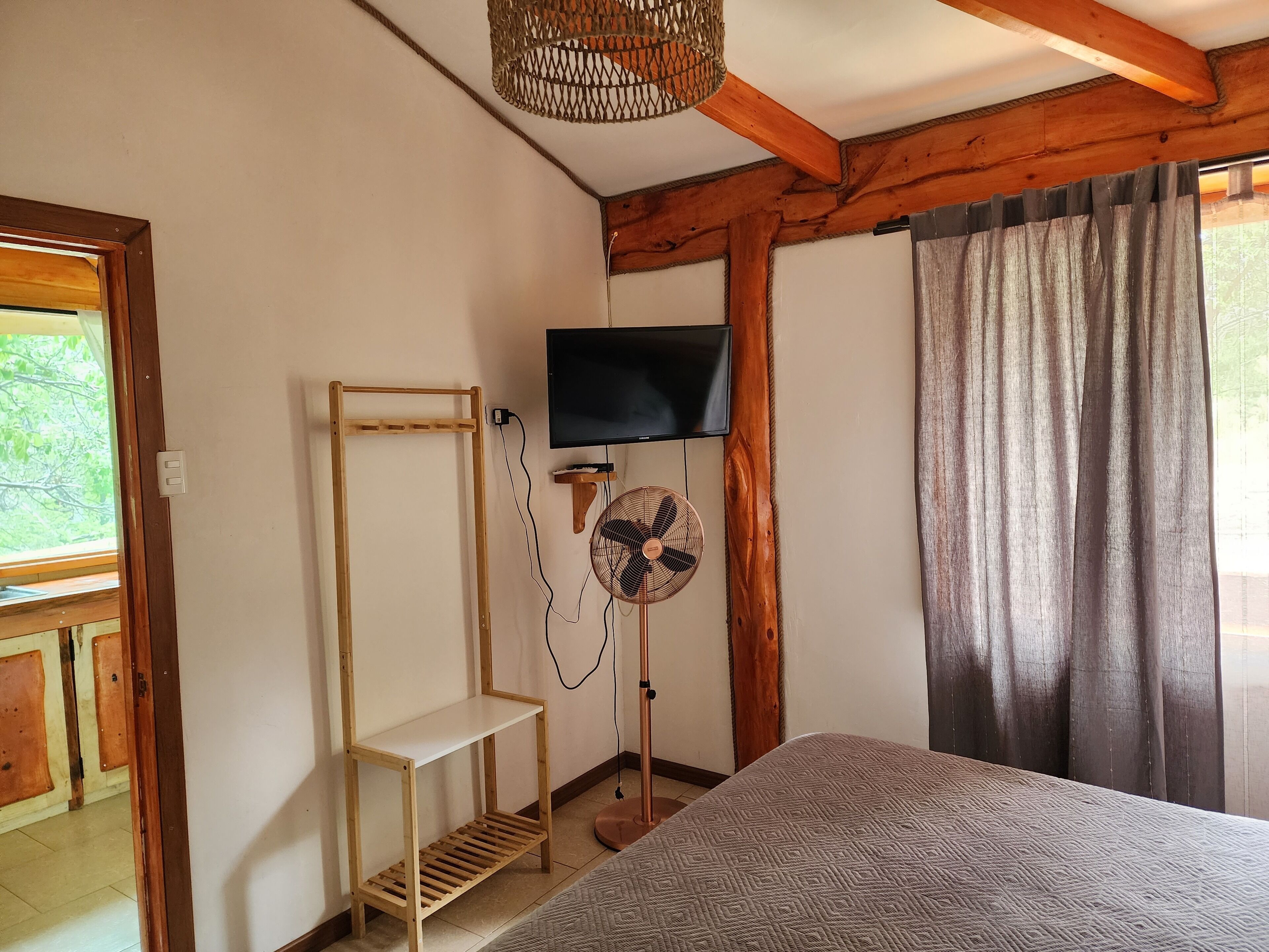 Een kamer met een bed, een aan de muur bevestigde televisie, een ventilator en een houten plankunit.