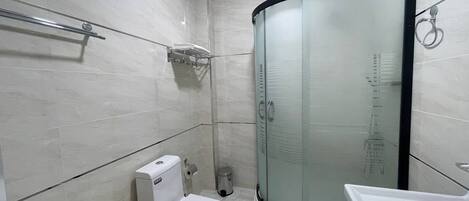 Une salle de bain moderne équipée de toilettes, d’un lavabo et d’une douche à parois de verre.