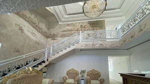 A grand room with a staircase, ornate chairs, and a luxurious sofa. - Anor Qal'a (Khiva)