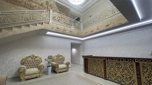 A grand room with ornate wall carvings, a chandelier, and two golden armchairs. - Anor Qal'a (Khiva)