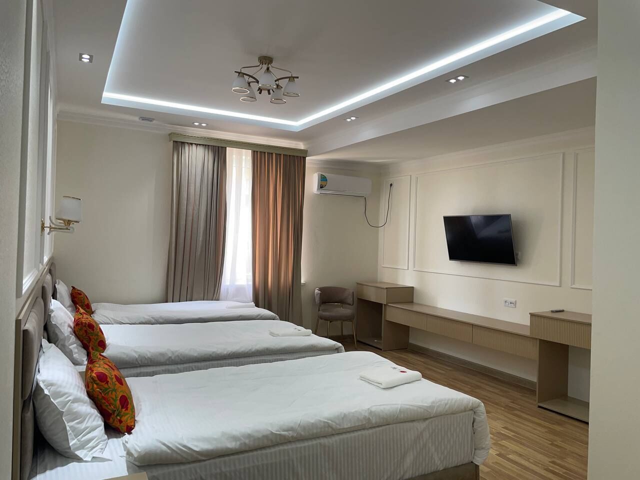 Habitación de hotel con dos camas, televisor, escritorio y silla.