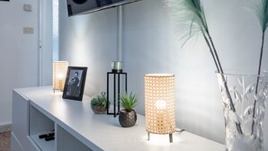 A modern living room with a white entertainment unit, a flat-screen TV mounted above it, and two decorative floor lamps. - Ariston Centro (Sanremo)