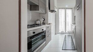 A narrow kitchen with a built-in oven, a gas stove, and a coffee maker. - Ariston Centro (Sanremo)