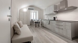 Un espace de vie compact comprenant un canapé, une table à manger et un coin cuisine.