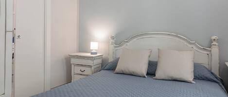 A bedroom with a bed, bedside table, and a nightstand.