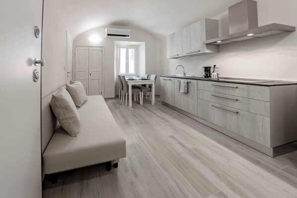 A modern kitchen with a dining area, a built-in sofa, and a kitchenette.
