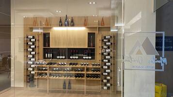 Una bodega con varias estanterías llenas de botellas de vino, un armario de madera y una vitrina de vidrio.