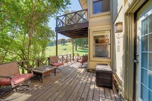Um deck de madeira com móveis para área externa, um espaço coberto e vista para uma paisagem verde.