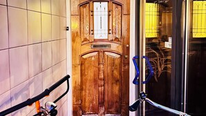 A wooden door with a sign, a bicycle rack, and a tiled wall. - Leiden City Centre Canal View Apartment in a 1750's building (Leiden)