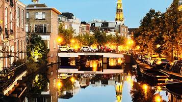 A canal with boats, a bridge, and buildings reflecting in the water.