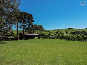 Un campo cubierto de hierba con un edificio y árboles.