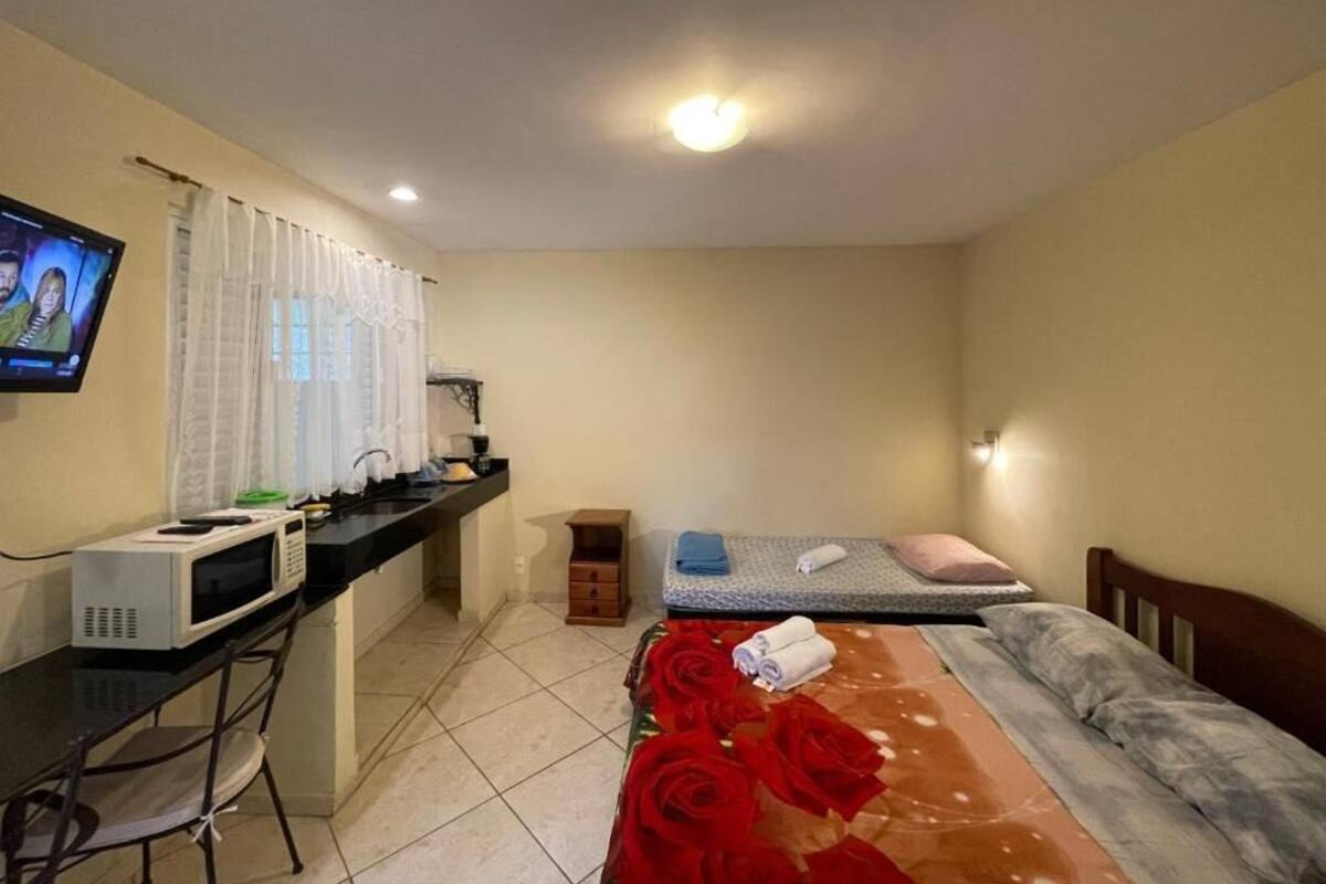 A hotel room with a bed, a desk with a computer, a microwave, and a TV.