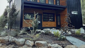 A modern two-story house with a wooden exterior, large windows, and a balcony.