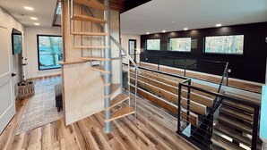 A modern interior with a spiral staircase, wooden flooring, and large windows.