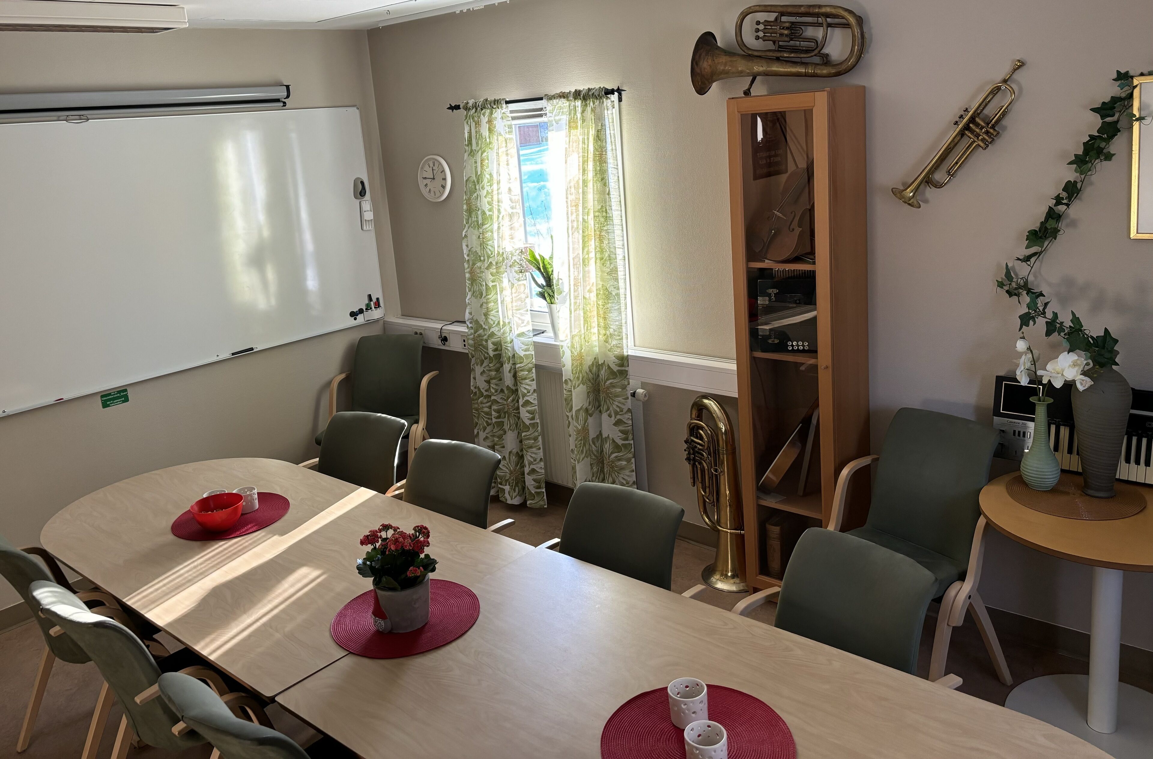 Uma sala de conferências com um quadro branco, um relógio e uma janela com cortinas.