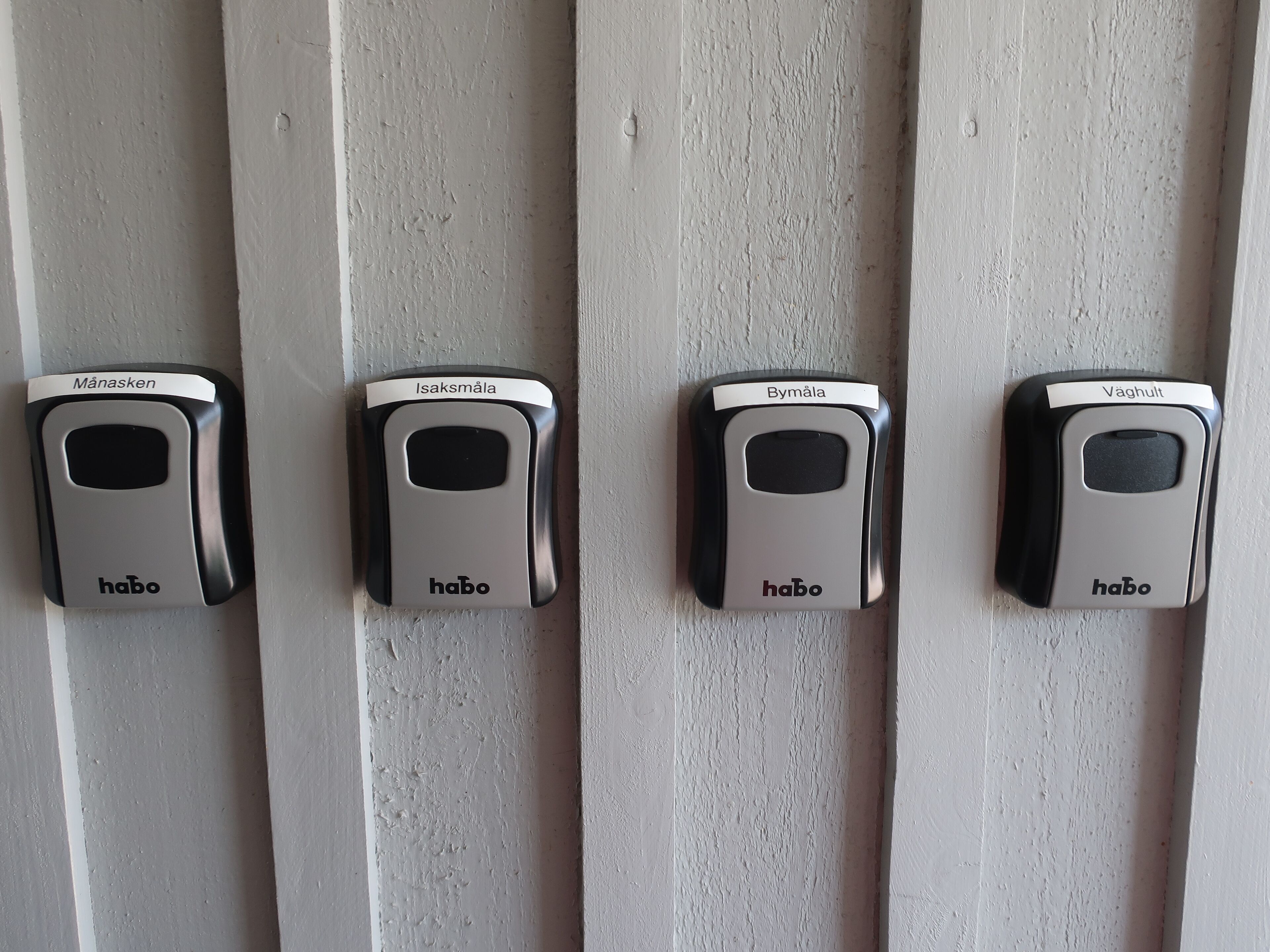 Four doorbell buttons labeled with names in a row on a white wall.