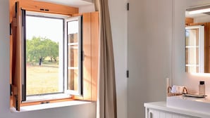 A bathroom with a window, wooden cabinets, a mirror, and a towel rack.