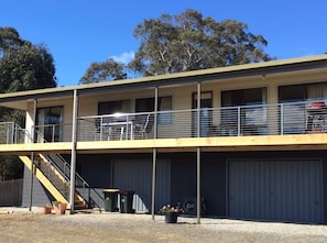 A two-story building with a balcony on the upper floor, a staircase leading to the upper level, and a garage at the base. - Bicheno Blue Horizon - The family holiday house! (Glamorgan-Spring Bay)