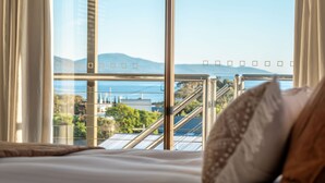 A hotel room with a large window offering a view of a cityscape and mountains. - Bicheno Blue Horizon - The family holiday house! (Glamorgan-Spring Bay)