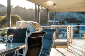 A table with two glasses and a grill on a balcony with a view of the landscape. - Bicheno Blue Horizon - The family holiday house! (Glamorgan-Spring Bay)