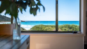 A room with a large window overlooking a beach and ocean. - Silver Moon at Half Moon Bay - Paradise! (Glamorgan-Spring Bay)